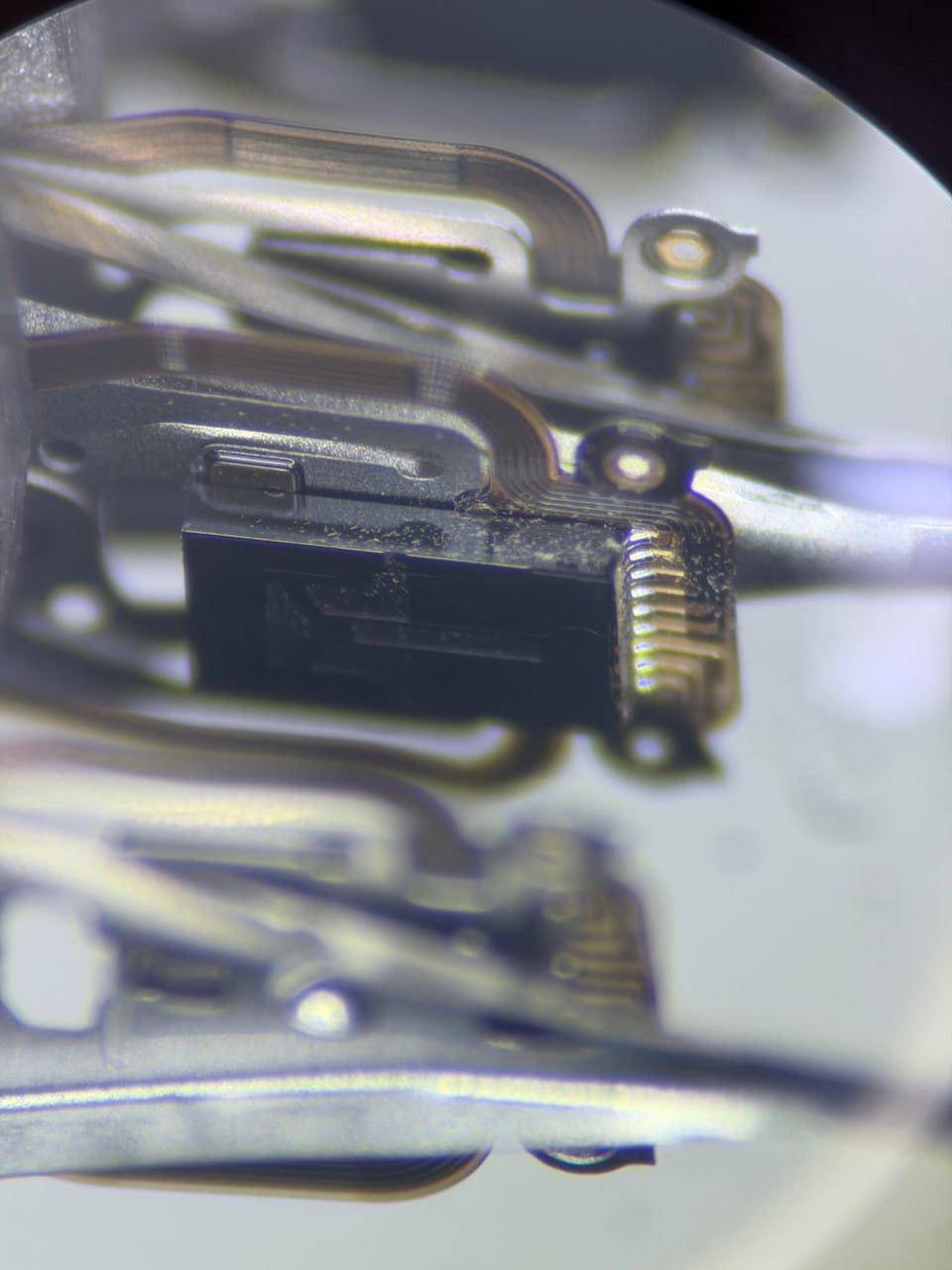 Microscope close-up of contaminated read/write head slider — hard drive contamination damage