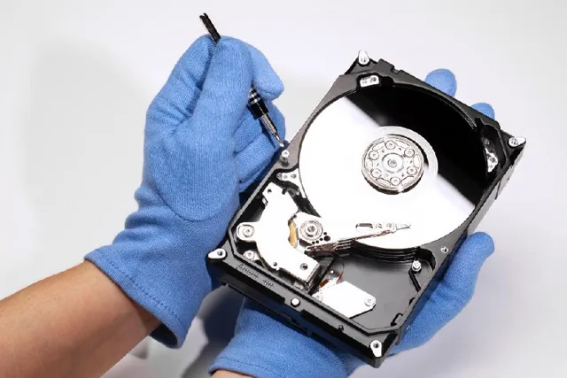 Data recovery technician working on hard drive with blue gloves